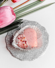 Decorated heart shaped cookies and sprinkles with a strawberry ice cream and flowers on white background . Valentine's day treat