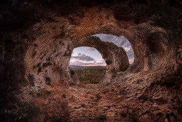 Sunset in the cave. Panoramic view of the interior of a cavern, at the entrance an arch crosses the top. Interior of the Cueva de los Arcos. Sunset in a large cave, with an arch at the entrance.  