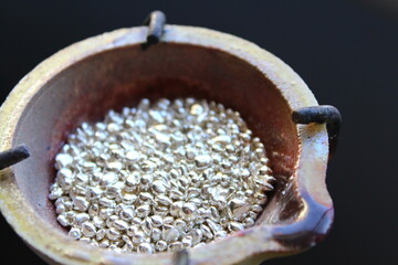 A ceramic crucible or melting pot with grains of sterling silver 925 for jewelry making after hand smelting in a workshop. One of the two major precious metals on the market.