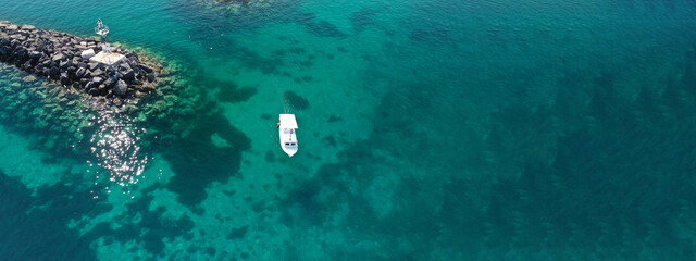 Aerial drone ultra wide photo of speed boat with wooden deck anchored in tropical exotic turquoise...