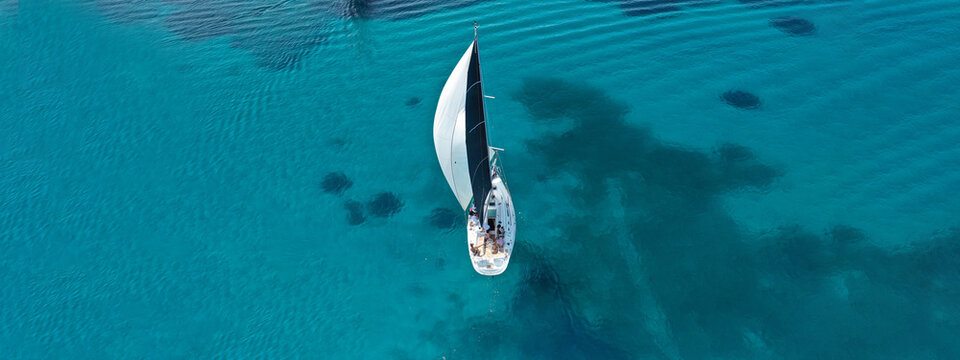 Aerial drone ultra wide photo of beautiful sail boat cruising tropical exotic bay with turquoise sea