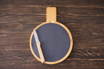 Wooden cutting board and knife on wooden background, place for text. Top view.