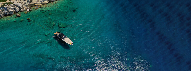 Aerial drone ultra wide photo of speed boat with wooden deck anchored in tropical exotic turquoise crystal clear sea bay