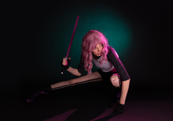 Punk rock sexy female assassin with pink hair wearing black, holding a weapon. © James Carroll