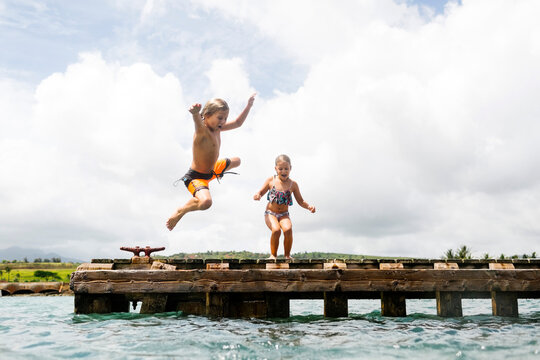 Boy (8-9) And Girl (6-7) Jumping Into Sea From Jetty