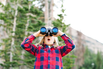 Boy (6-7) using binoculars in forest