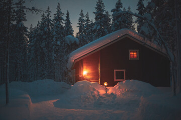 A night view of cozy wooden scandinavian cabin cottage chalet house covered in snow near ski resort...