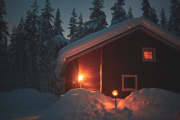 A night view of cozy wooden scandinavian cabin cottage chalet house covered in snow near ski resort...