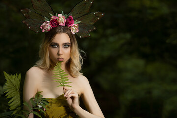 Portrait of Caucasian Female Posing With Decorative Butterfly Garland and Holding Green Leave...