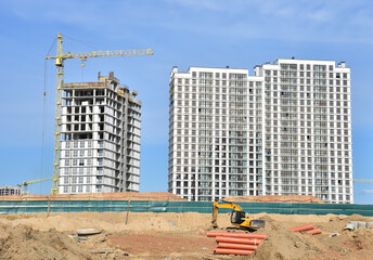 Tower cranes in action on blue sky background. Excavator dig ground for foundation pit at...