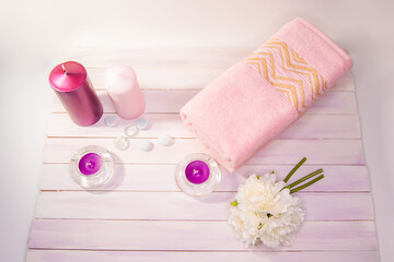 Spa still life - a flowers and towels on a wooden  background. Beige, pink and white tones. The view from the top.