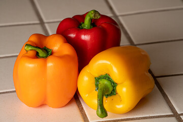Three bell peppers waiting to be eaten. Red bell pepper, yellow bell pepper and orange bell pepper.