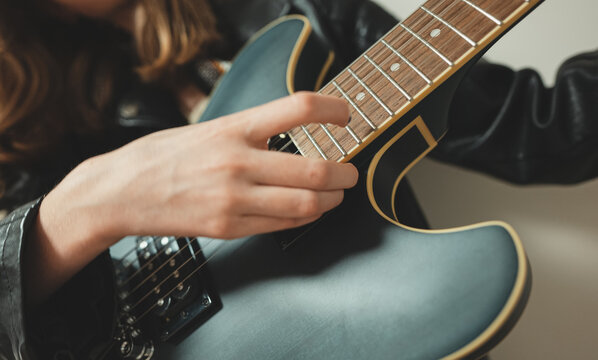 Girl playing on the semi-acoustic guitar. Close-up view.
