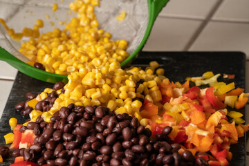 Corn, black beans and bell peppers being prepared for a meal.