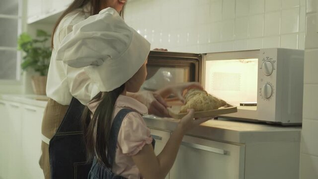Asian Little girl helping mother bake bread in the kitchen.