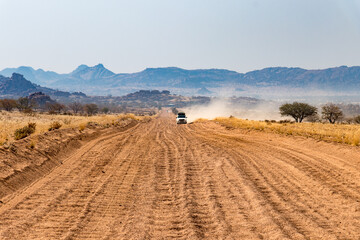 Fototapeta na wymiar Washboard gravel road in Namibia - upcoming cars giving big dust clouds 