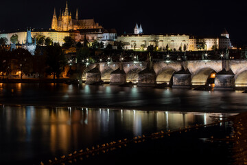 Fototapeta na wymiar old illuminated prague castle and charles bridge and st. vita church lights from street lights are reflected on the surface of the vltava river in the center of prague at night in the czech republic
