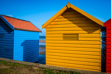 Fototapeta na wymiar Colourful bathhouses at the beach of the North Sea in Whitby, Yorkshire, United Kingdom