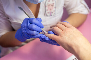 Obraz na płótnie Canvas Closeup hands in gloves of a qualified manicurist doing man's nails. Men's manicure in salon
