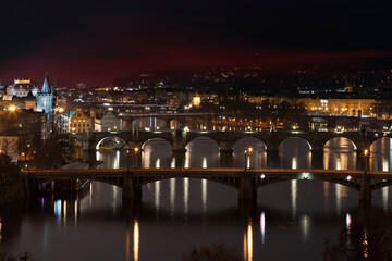 .view of the Vltava river and the bridges on it between them and the Charles Bridge and light from street lighting and the roofs of buildings in the center of Prague at night