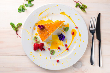 Cheesecake decorated with edible flowers on white plate. a piece of cheesecake on a white wooden table