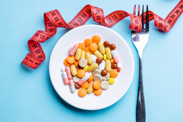heap of pills, tablet, capsules on a plate over blue background. outer space. pill diet concept