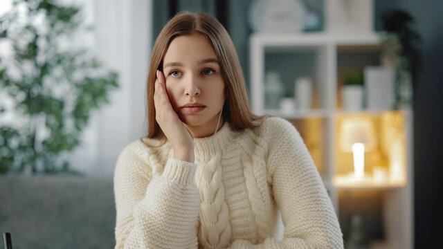 Cute young woman with brown hair feeling tired because of long studying at home. Exhausted student in casual outfit sigh heavily while sitting at table.