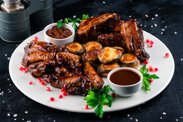 grilled chicken wings and grilled ribs BBK on a round wooden Board