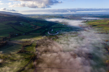 Aerial view of patches of fog along a river in a rural setting (River Usk, Wales)