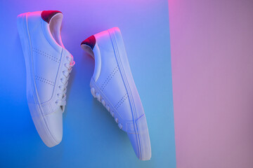 Pair of sneakers on color background, top view