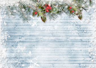 Christmas and New Year beautiful background with snow-covered branches, holly and snowflakes on snowy wooden boards. Christmas card