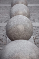 row of granite balls on the pedestrian sidewalk paved with stone tiles, cityscape urban street architecture objects, nobody.