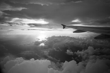 Fototapeta na wymiar Black and white picture of airplane wings against cloudy sky