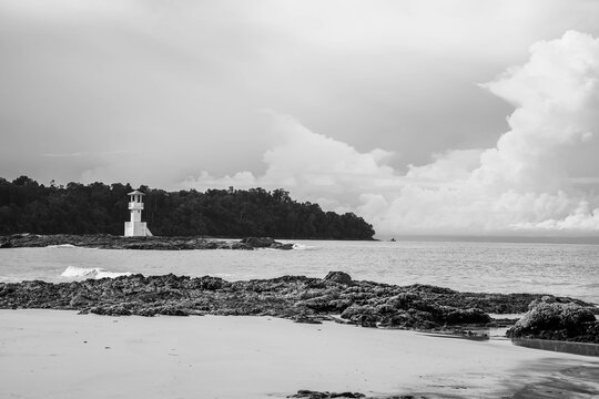 Black and white picture of sea shore with light house background.