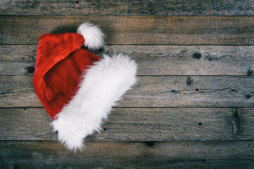 Obraz na płótnie Canvas Red Santa Christmas hat laid on rustic wooden background.
