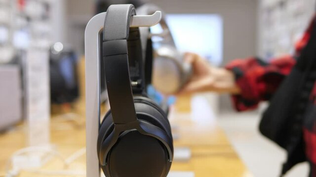 Female Hand Choosing Headphones In The Electronics Store. Close Up.