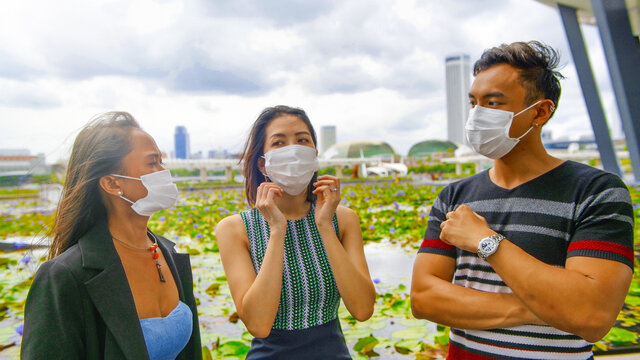 Three Asian Young Friends Standing Outdoor In The City Talking And Wearing Face Masks In Covid Coronavirus Pandemic