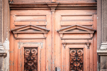 Fototapeta na wymiar Detail of an old vintage orange wooden door on the front entrance of a residential building in Vojvodina, Serbia, in central Europe