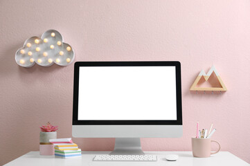Comfortable workplace with modern computer on table near pink wall. Space for design