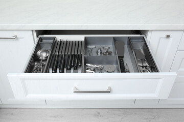 Open drawer with stainless steel utensil set. Order in kitchen