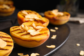 Delicious grilled peaches with almond flakes on grey table, closeup