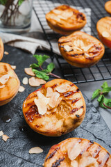 Delicious grilled peaches with almond flakes on slate plate, closeup