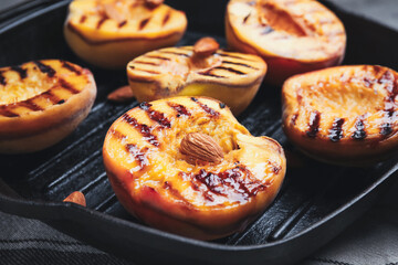 Delicious grilled peaches with almonds in pan, closeup