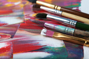 Fototapeta premium Set of different brushes on abstract colorful paint, closeup