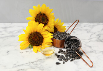 Sunflowers, oil and seeds on white marble table