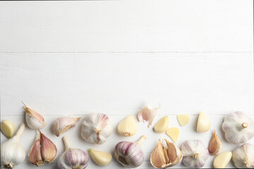 Fresh organic garlic on white wooden table, flat lay. Space for text
