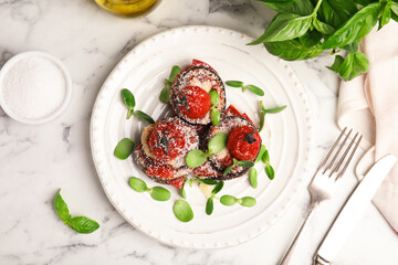 Baked eggplant with tomatoes, cheese and basil served on white marble table, flat lay
