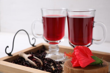 Beautiful Hibiscus flower and delicious tea on wooden tray, closeup