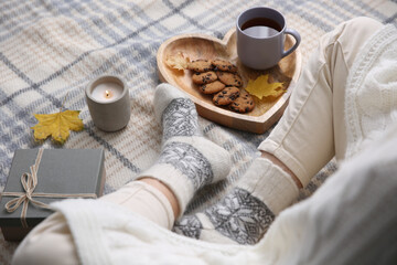 Woman wearing warm socks on checkered plaid, closeup. Cozy season