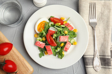 Delicious crab stick salad served on grey table, flat lay